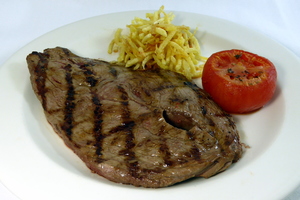 Grilled veal steak with baked tomatoes and chips